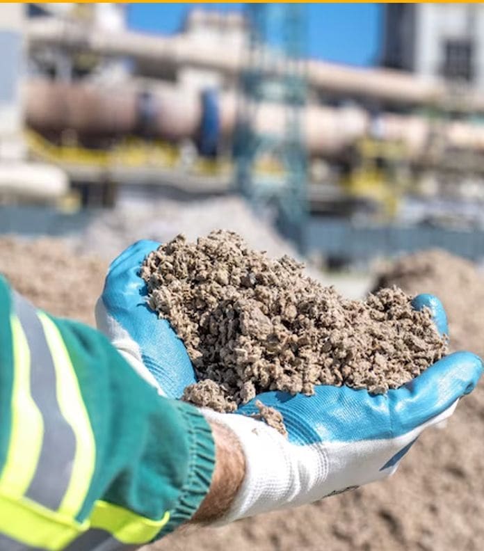 Gloved hands holding a handful of fill soil